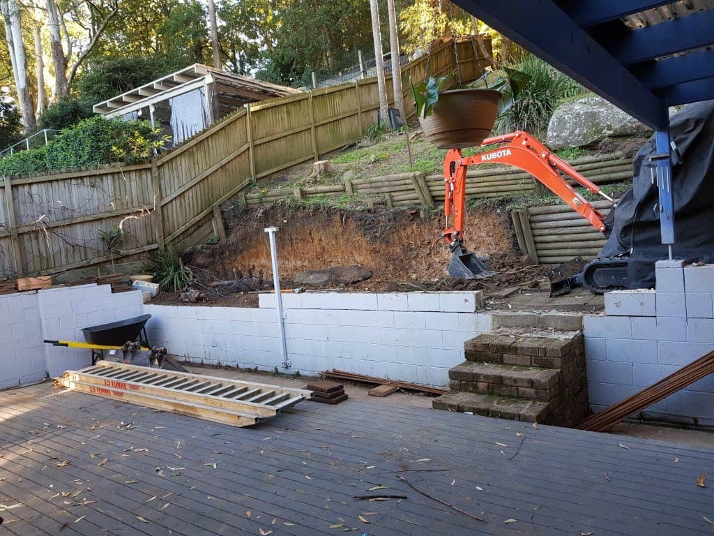 mini excavator on retaining wall