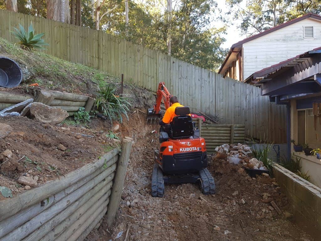 mini excavator digging retaining wall